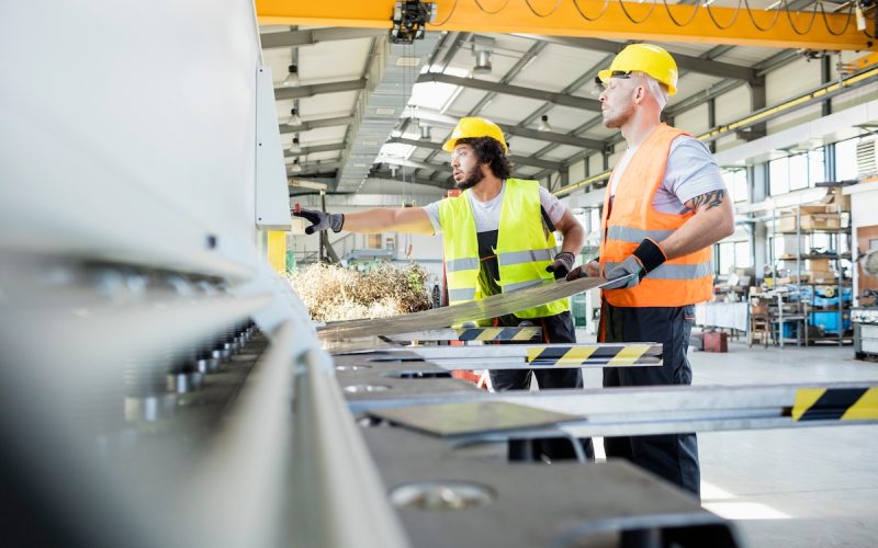 Male manual workers manufacturing sheet metal at industry